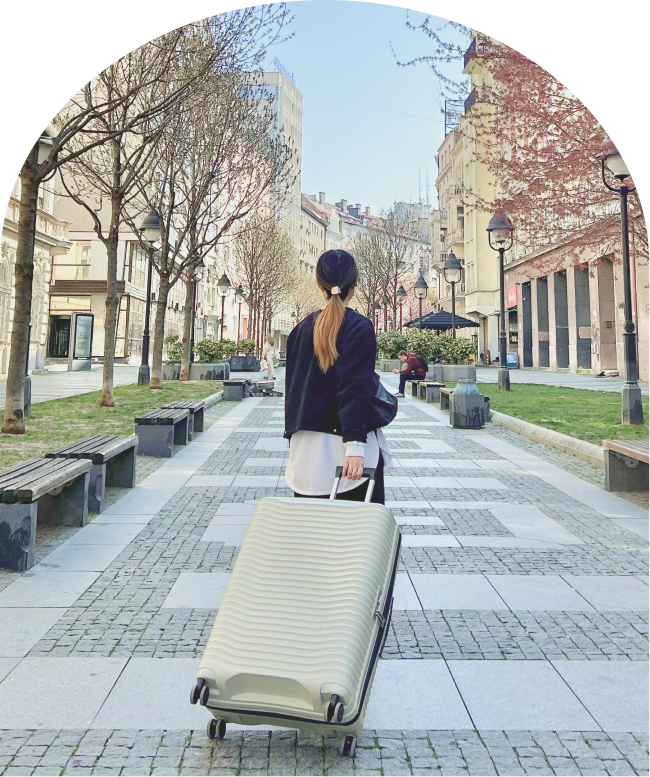 スーツケースを引いて海外の街を歩く女性の後ろ姿